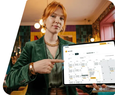 A salon owner pointing at the Bookio booking calendar on a tablet